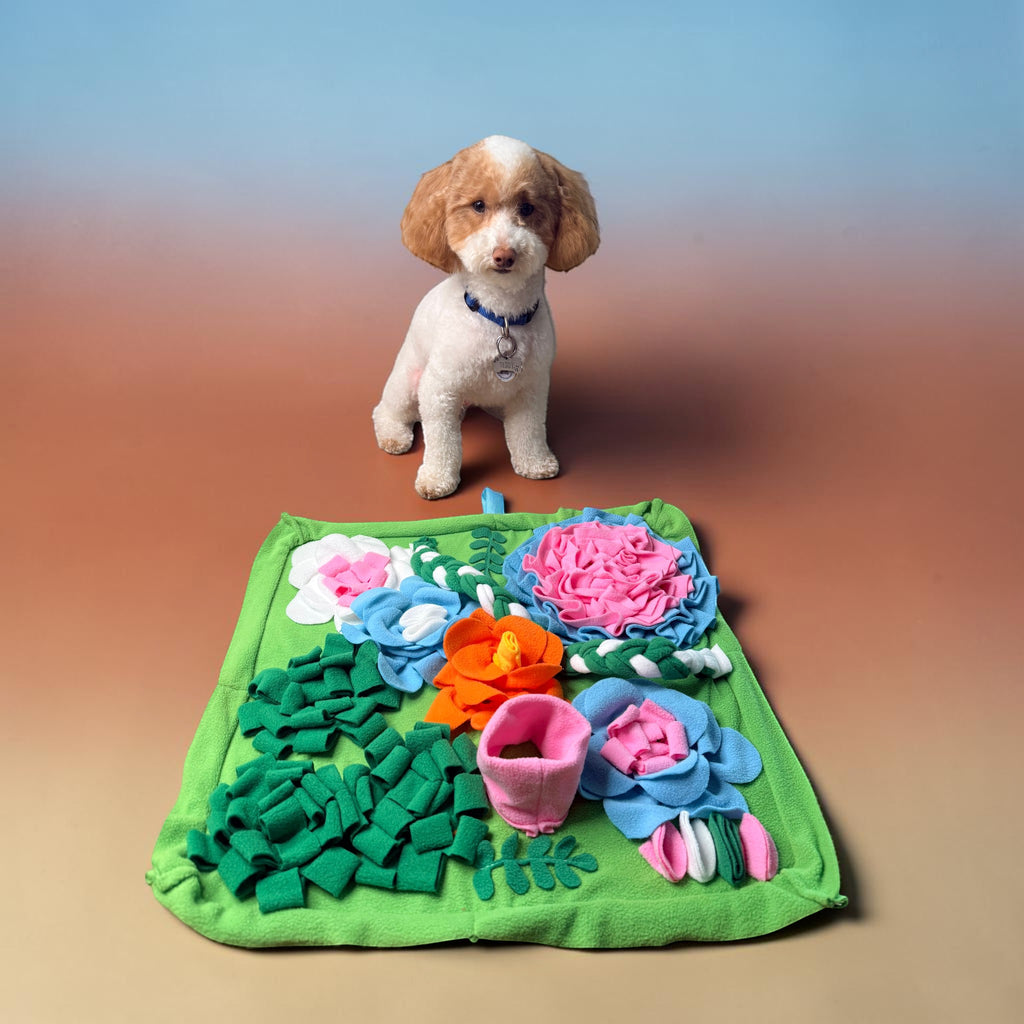 FurSniff floral snuffle mat with colorful fleece petals in pink, blue, and orange. A small white dog sits behind it.