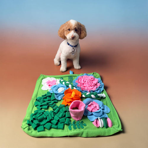 FurSniff floral snuffle mat with colorful fleece petals in pink, blue, and orange. A small white dog sits behind it.