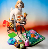 Dog standing on a small bicycle with various toys around
